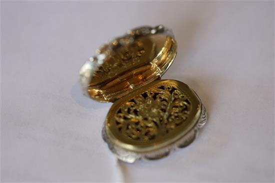 A Victorian silver cusped oval vinaigrette by Nathaniel Mills, the lid engraved with houses,